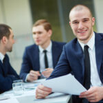 Young businessman with document looking at camera in working environment